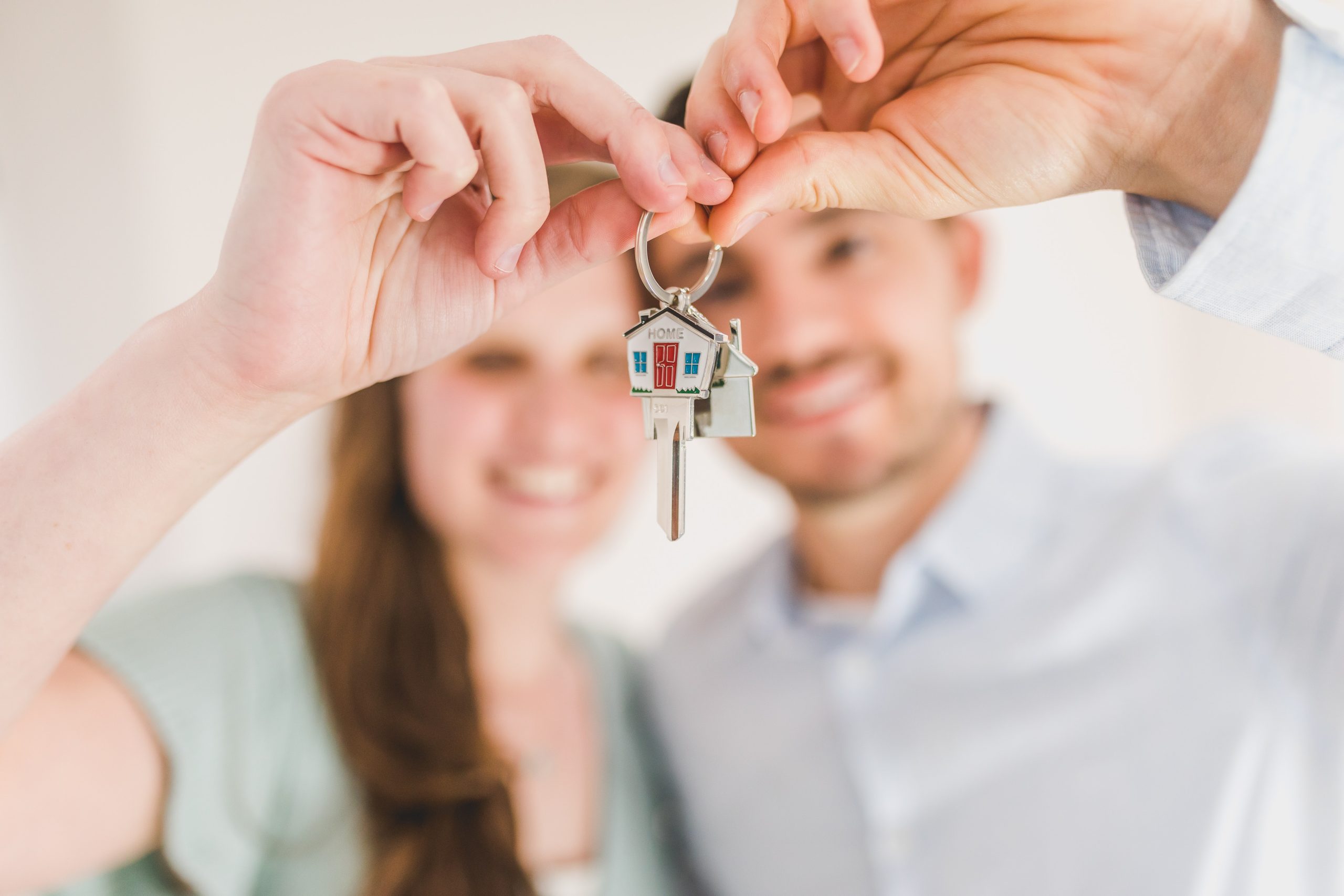 Pareja sosteniendo un llavero que dice home refiriendose a su nuevo hogar