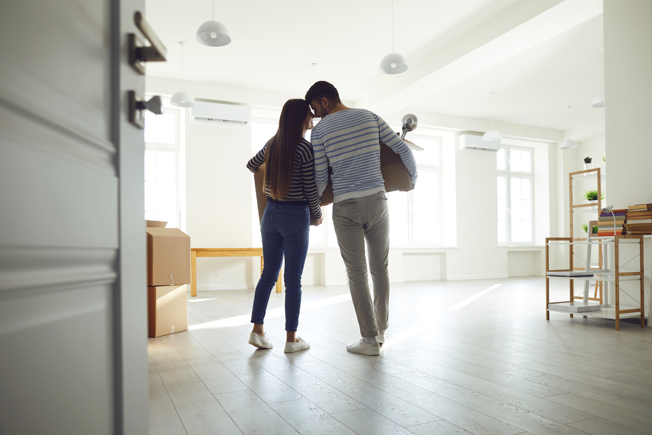 Rear view moving. Young couple family with boxes to move in a new house room. Buying sale, rent, real estate mortgage.