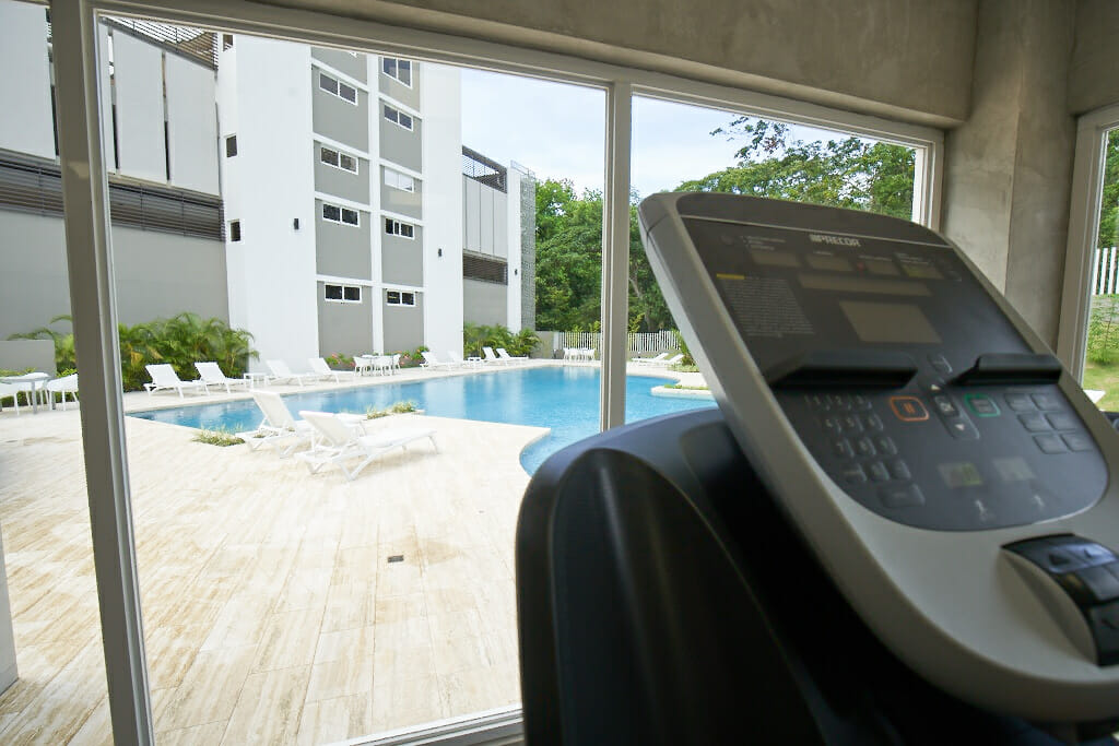 Caminadora en gimnasio con vista a piscina de Península Norte