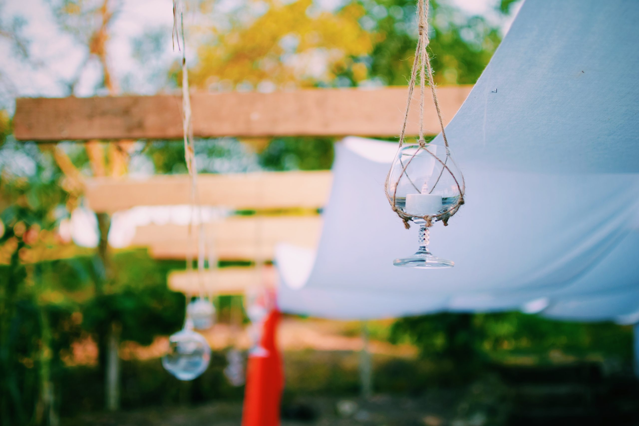 Pérgola en exteriores decorada con portavelas colgantes hechos de copas de vidrio