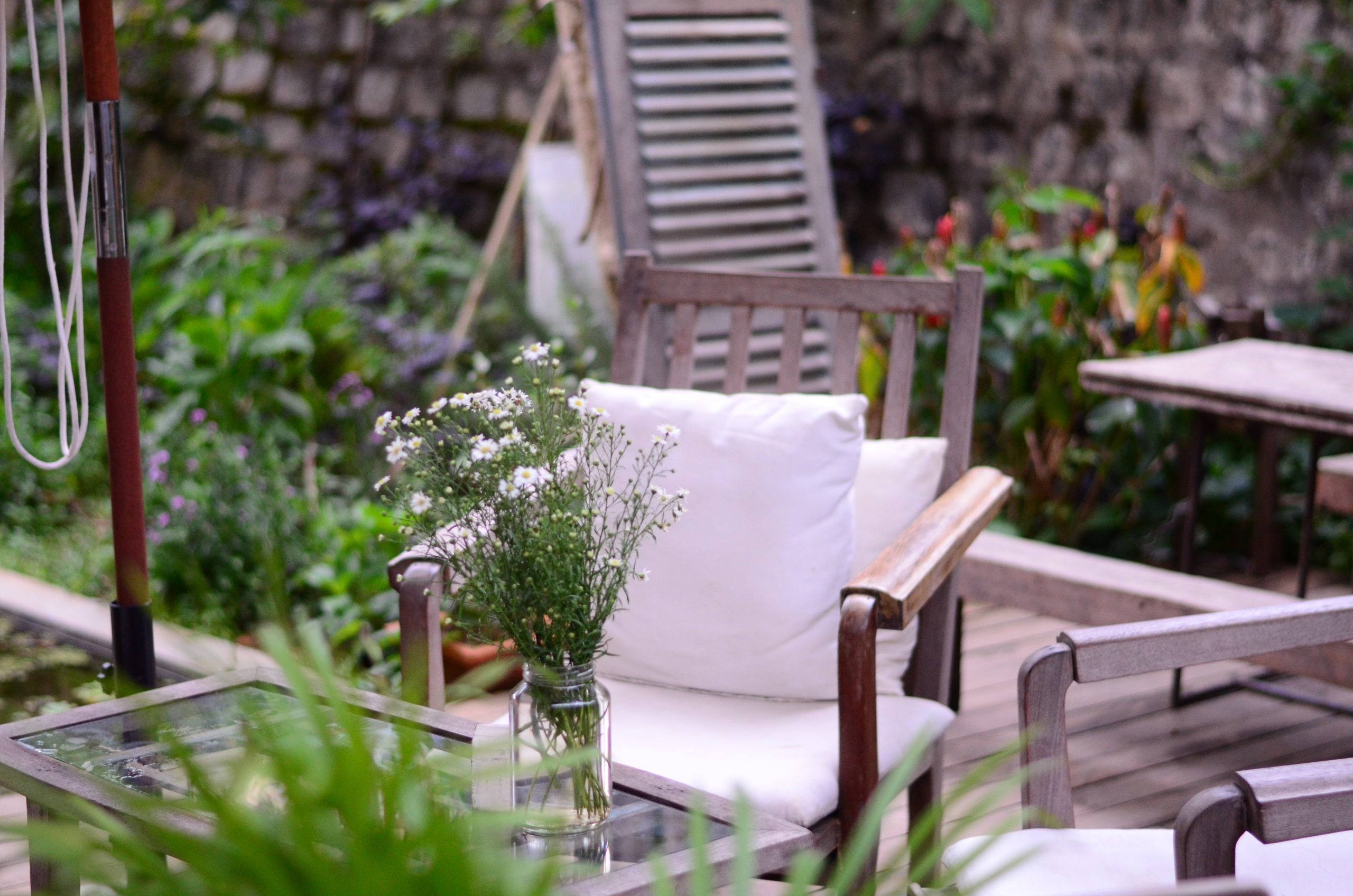 Sala de estar en exteriores con mesa de centro decorada con jarra de vidrio llena de flores