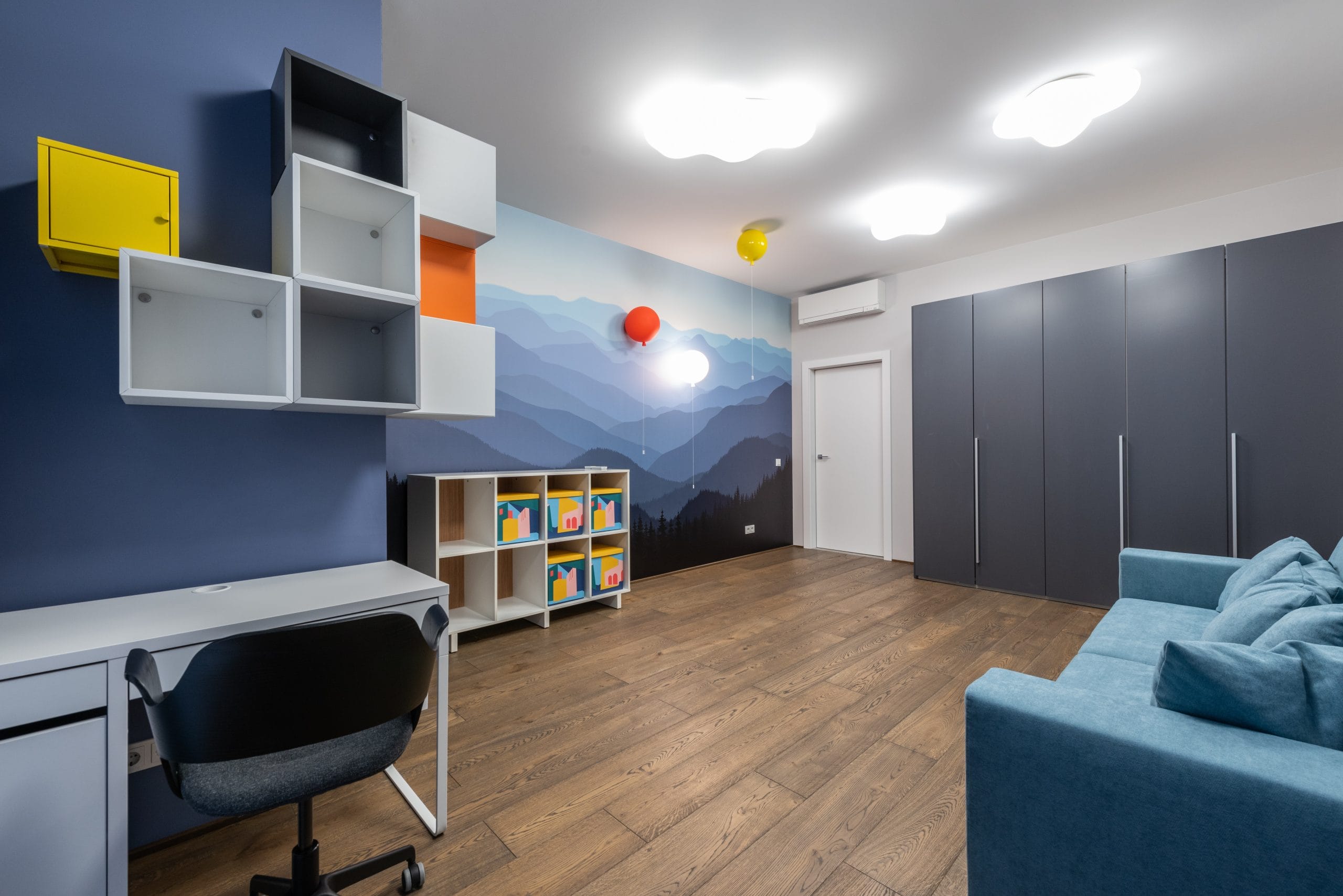 Habitación decorada con estantes, sofá y escritorio, y un papel tapiz en tonos azules.